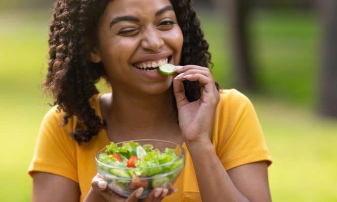 pretty black girl eating fresh vegetable salad and winking at green 768 e1672319048878